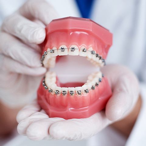 Orthodontist holding model of traditional braces in Grayslake