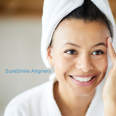 Woman using SureSmile clear aligners looking at smile in mirror