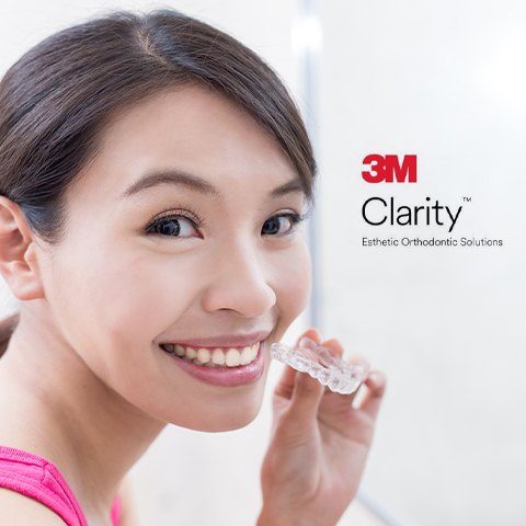 Woman holding 3 M Clarity aligners clear braces tray