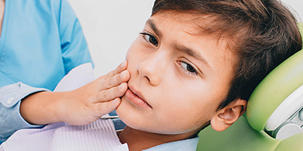 Young boy with loose palatal expander holding cheek