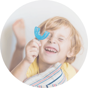 Smiling little boy holding phase one orthodontics mouth guard