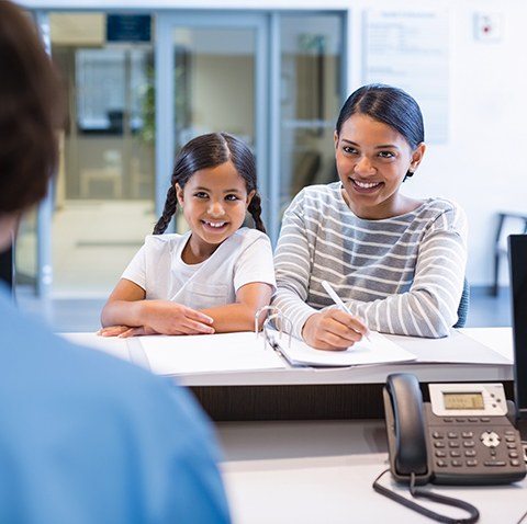 Mother and child completing dental insurance paperwork