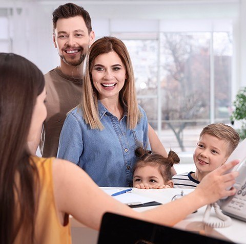 Family checking in at orthodontic office reception desk