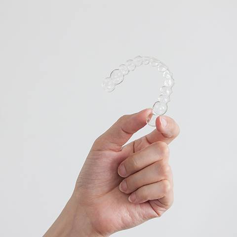 Hand holding an Invisalign tray