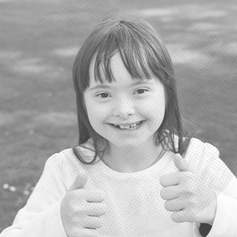Young girl giving two thumbs up after special needs orthodontics
